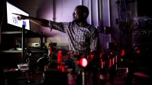 Professor in a dark room points at a bright monitor